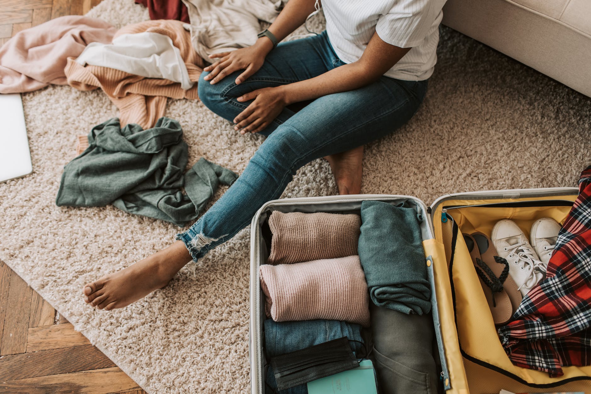 DG Speaks - Travel - Female Digital Nomad Packing - Image of a woman sitting on the floor, expertly packing her suitcase – an inviting glimpse into the organized and practical approach for female digital nomads heading to paradise.