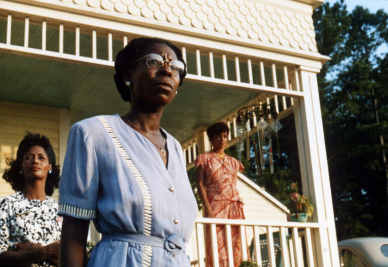 DG Speaks - Pop Culture - Film Review - "The Color Purple" - Whoopi Goldberg as Celie standing on the porch with other women.