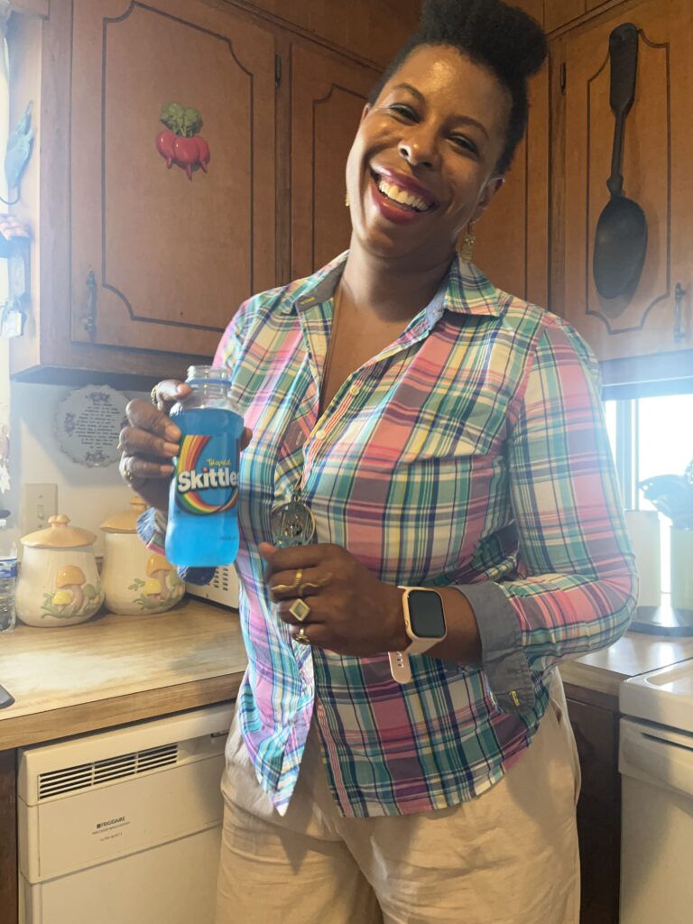 Mercedes in a colorful plaid shirt holding a branded Skittles drink in a vintage-style kitchen, illustrating the art of food branding with vibrant product placement.