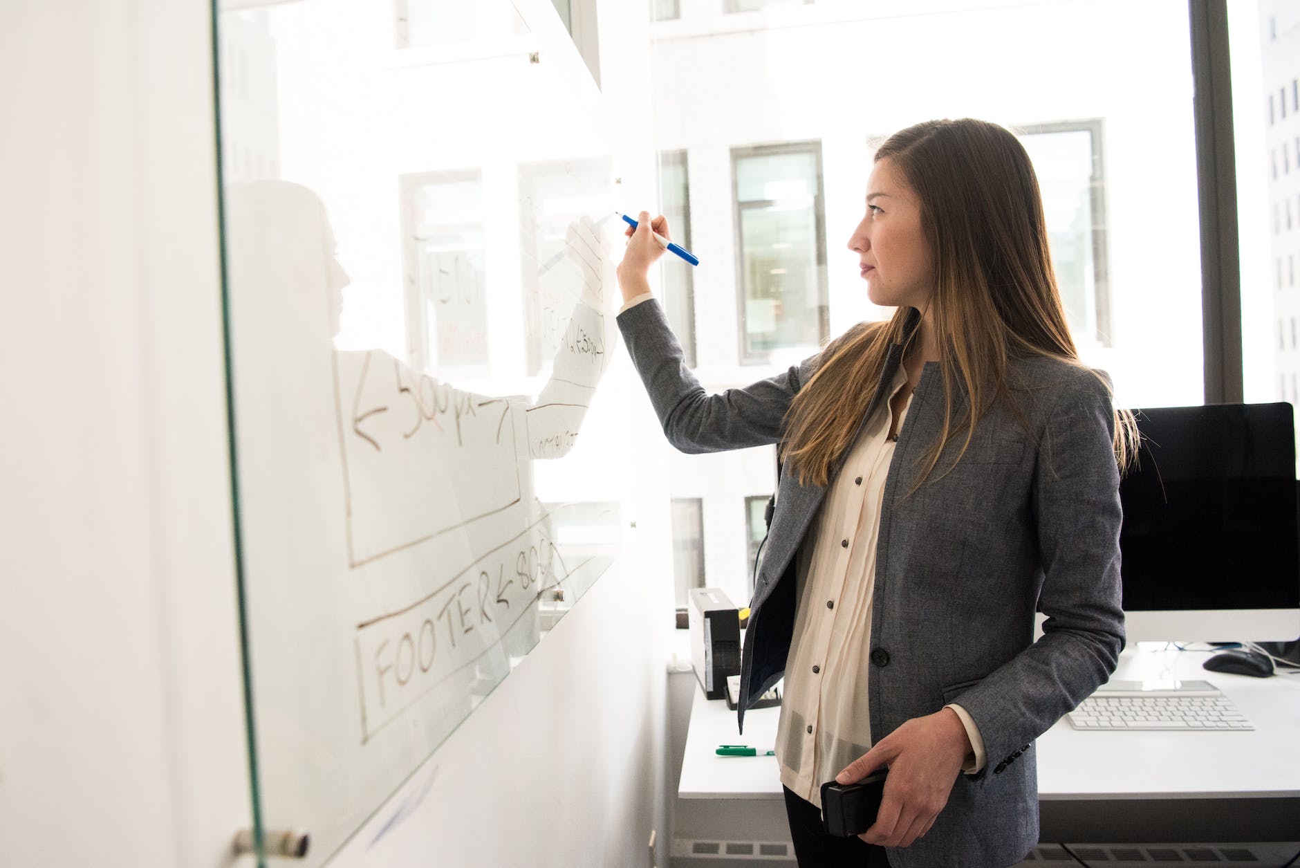 DG Speaks - Money - Consulting - Competitor Research - woman wearing gray blazer writing on dry erase board