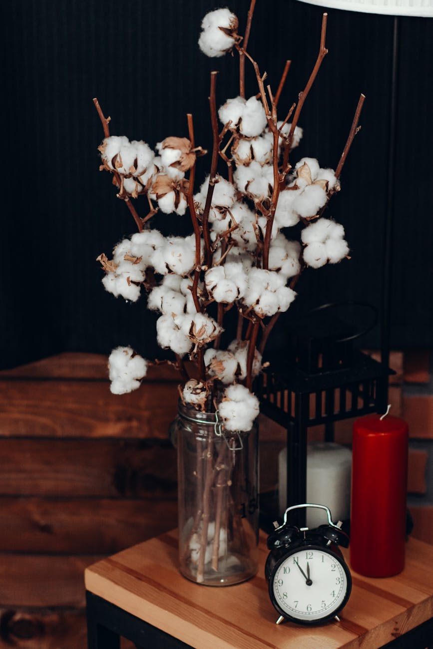 white cotton flowers in vase beside clock