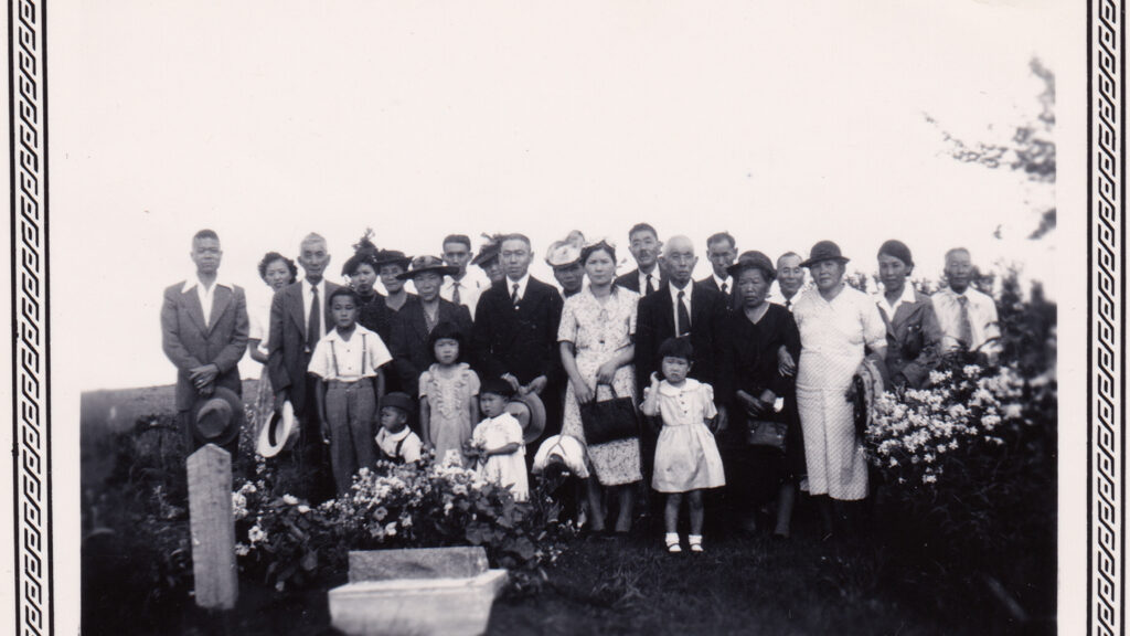 A still from A Stream of Echoes, featuring a family photo at a grave, symbols of memory and history.