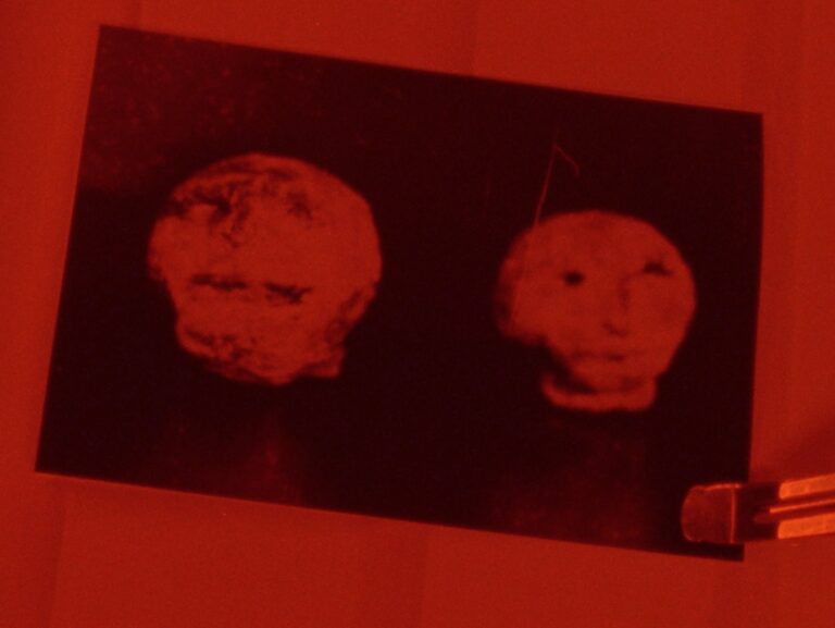 A still from Hexham Heads, showing a hauntingly lit stone heads unearthed in a dark, mysterious setting.