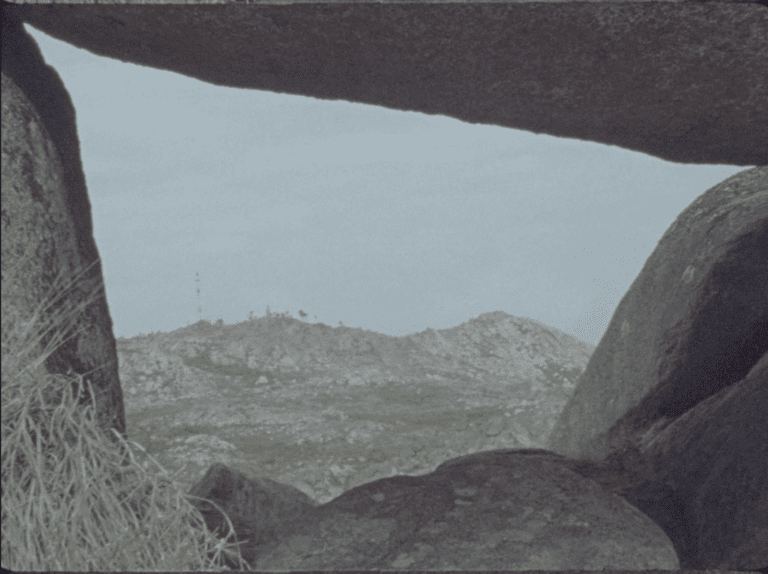 Still from Our Lady Who Burns showing the view of an open space between boulders