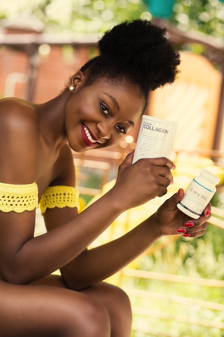 A joyful woman outdoors holding skincare products, showcasing beauty and wellness.