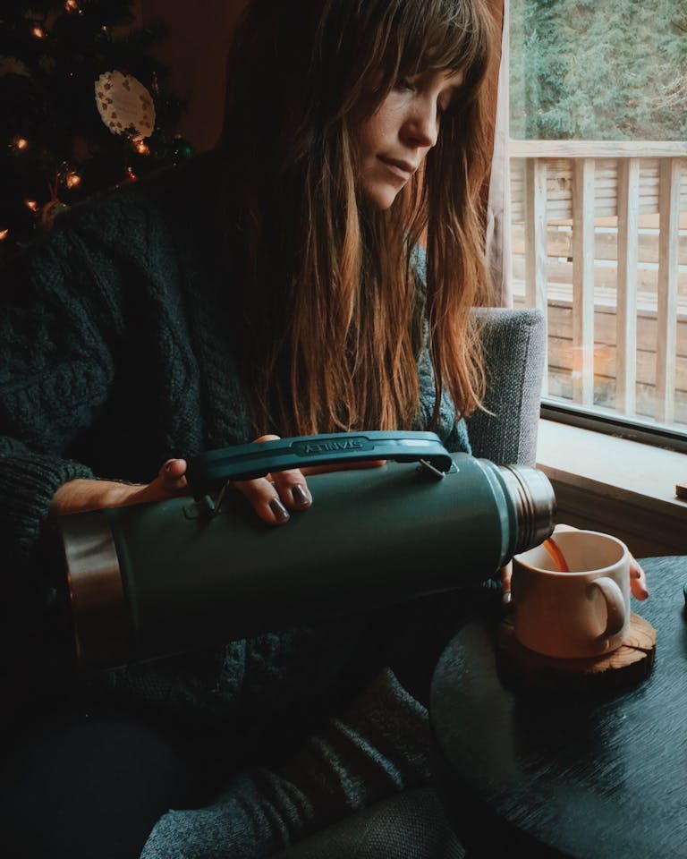 Woman pouring coffee from her Stanley cup thinking of the Stanley recall