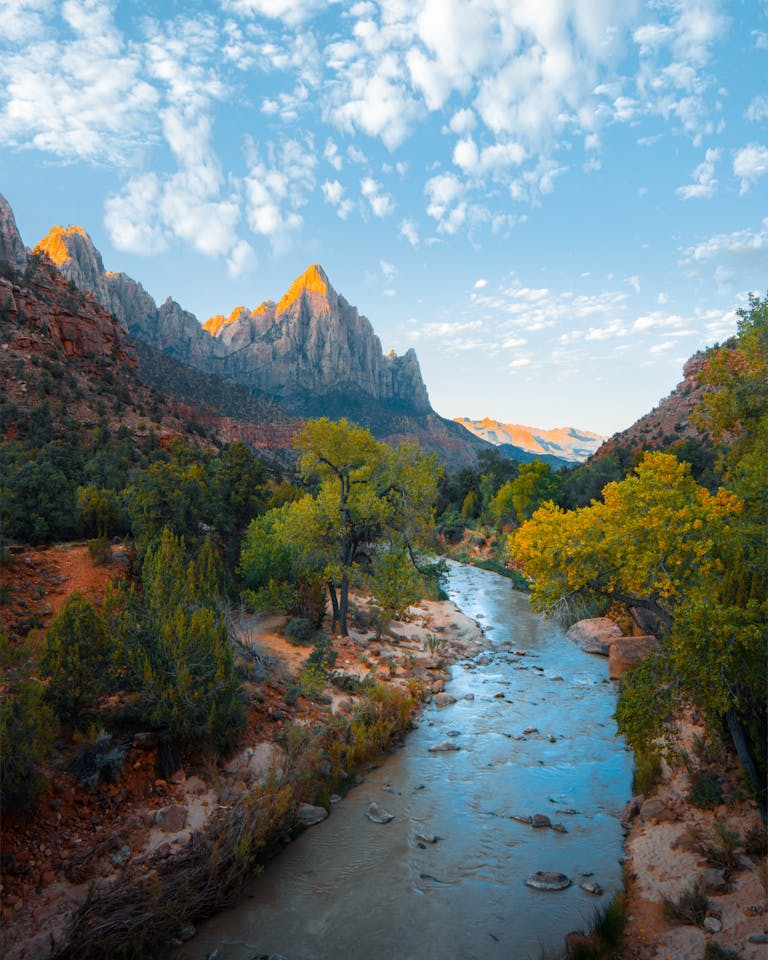 Majestic mountain landscape with a tranquil river in Zion National Park under a vibrant sky.