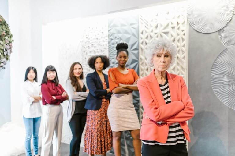 A diverse group of business women standing together in a modern office setting displaying leadership and confidence.