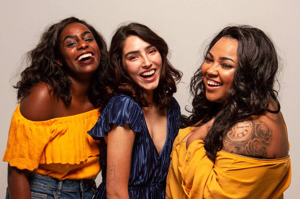 Joyful group of diverse women laughing together in bright outfits. Women who lead!