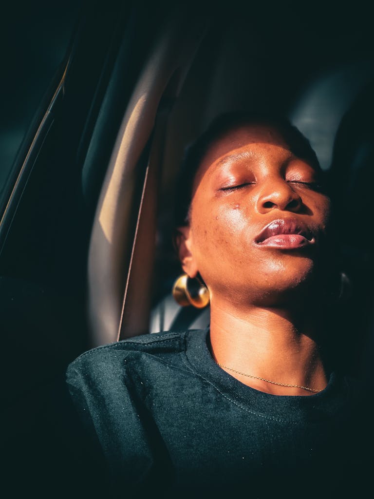 Low magnesium. A woman peacefully sleeps in a sunlit car interior, exuding tranquility and warmth.