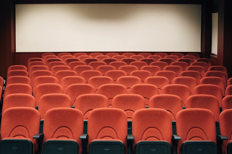 A spacious theater with empty red seats and a large screen, ready for the next audience. Tribeca