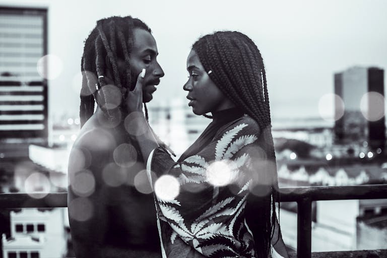 Black leads without Black romantic partners in film - A romantic black and white photo of a couple embracing on a city rooftop with bokeh effect.