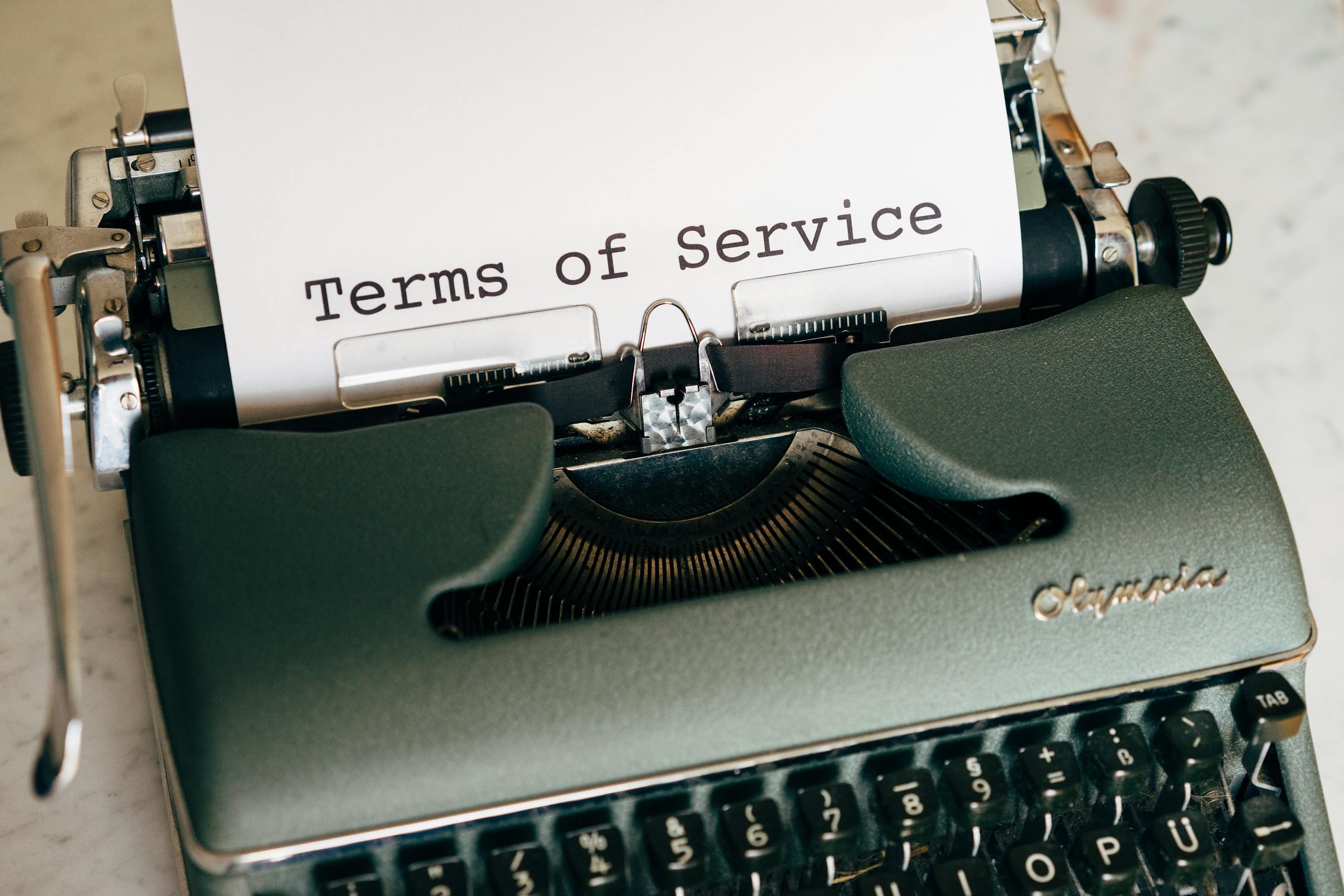 DG Speaks - Close-up of a vintage typewriter printing 'Terms of Service' on paper, ideal for legal and business themes.
