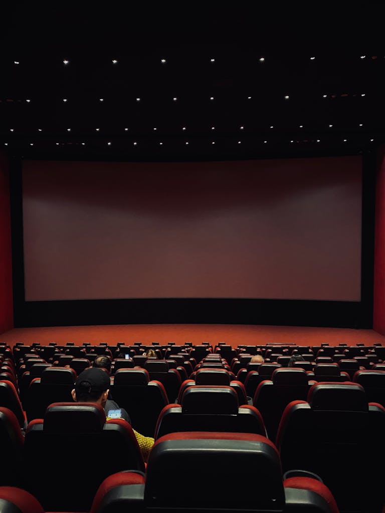 Dimly lit cinema hall with red seats and a blank screen. Minimal audience. SXSW