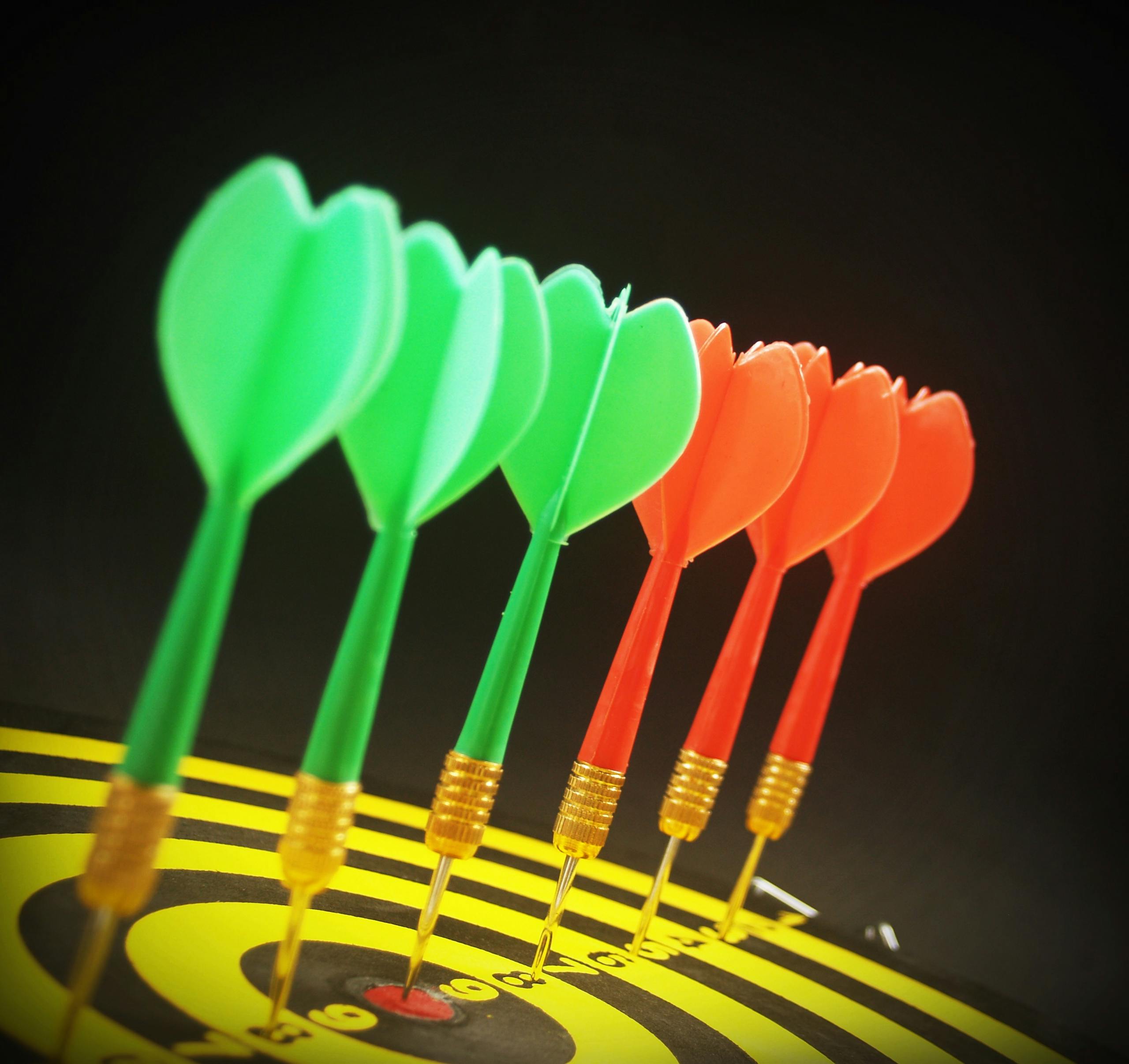 Mission and vision. -Close-up of colorful darts perfectly aligned on a dartboard target.