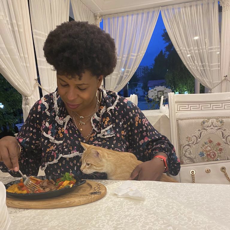 The Food That Feels Like a Love Letter to Place - Mercedes enjoying a lovely meal in Uzbekistan with a pretty kitty friend