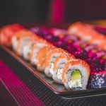 A vibrant sushi platter featuring a variety of colorful sushi rolls with salmon, avocado, and cream cheese.