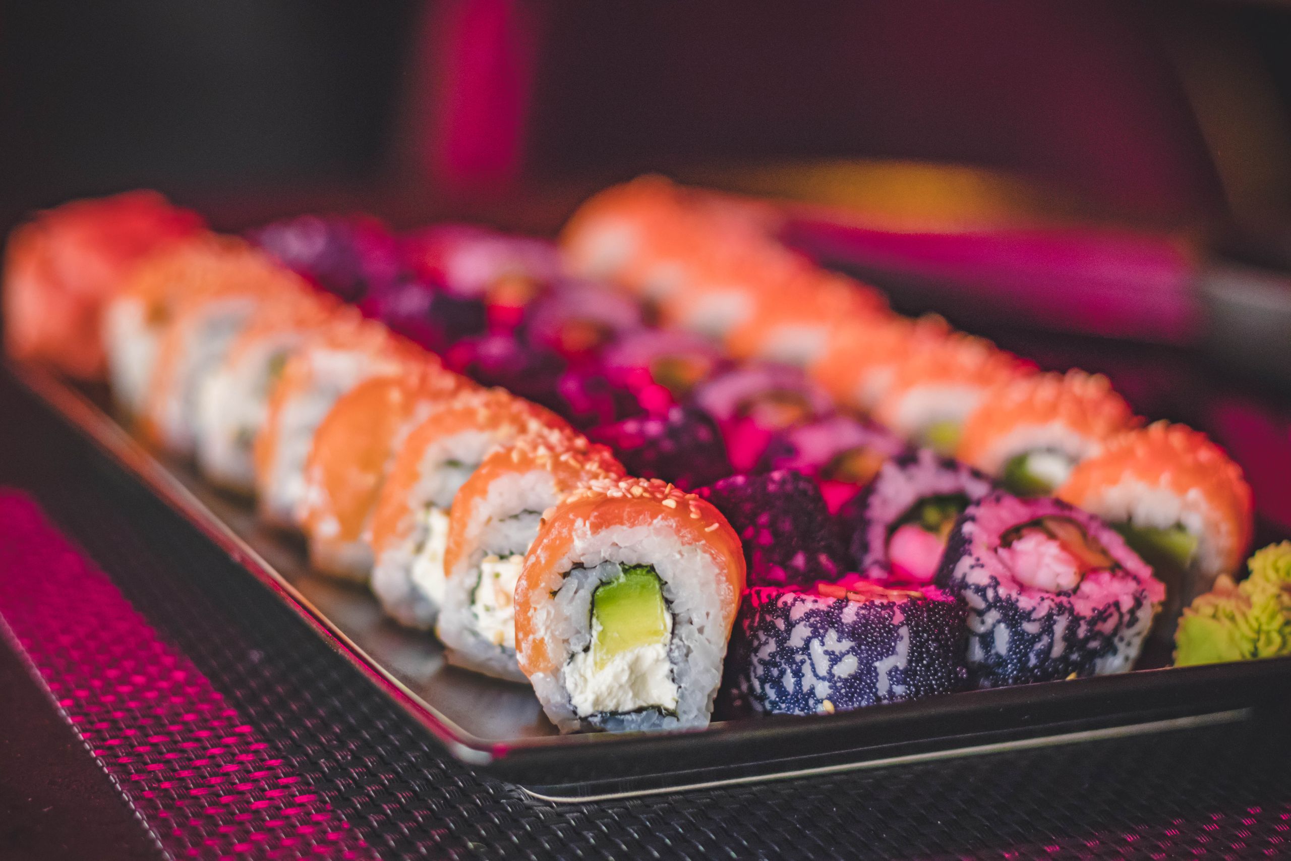 A vibrant sushi platter featuring a variety of colorful sushi rolls with salmon, avocado, and cream cheese.