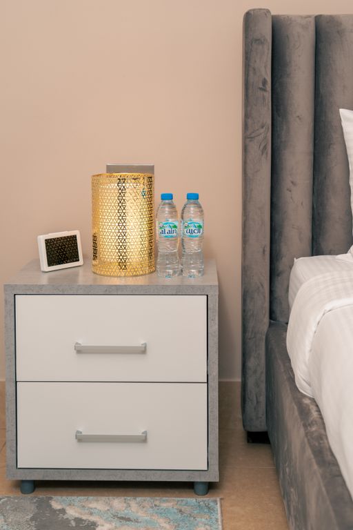Airbnb Amenities That Guests Actually Notice - Stylish nightstand setup in a Dubai hotel room featuring a lamp, water bottles, and neat decor.