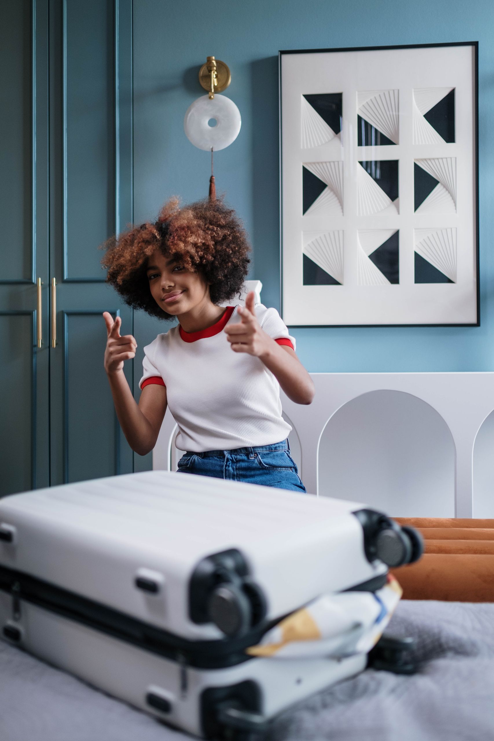 Airbnb Check-In Tips: How to Create a Smooth Arrival for Every Guest - Curly-haired woman giving thumbs up beside packed luggage in a modern home.