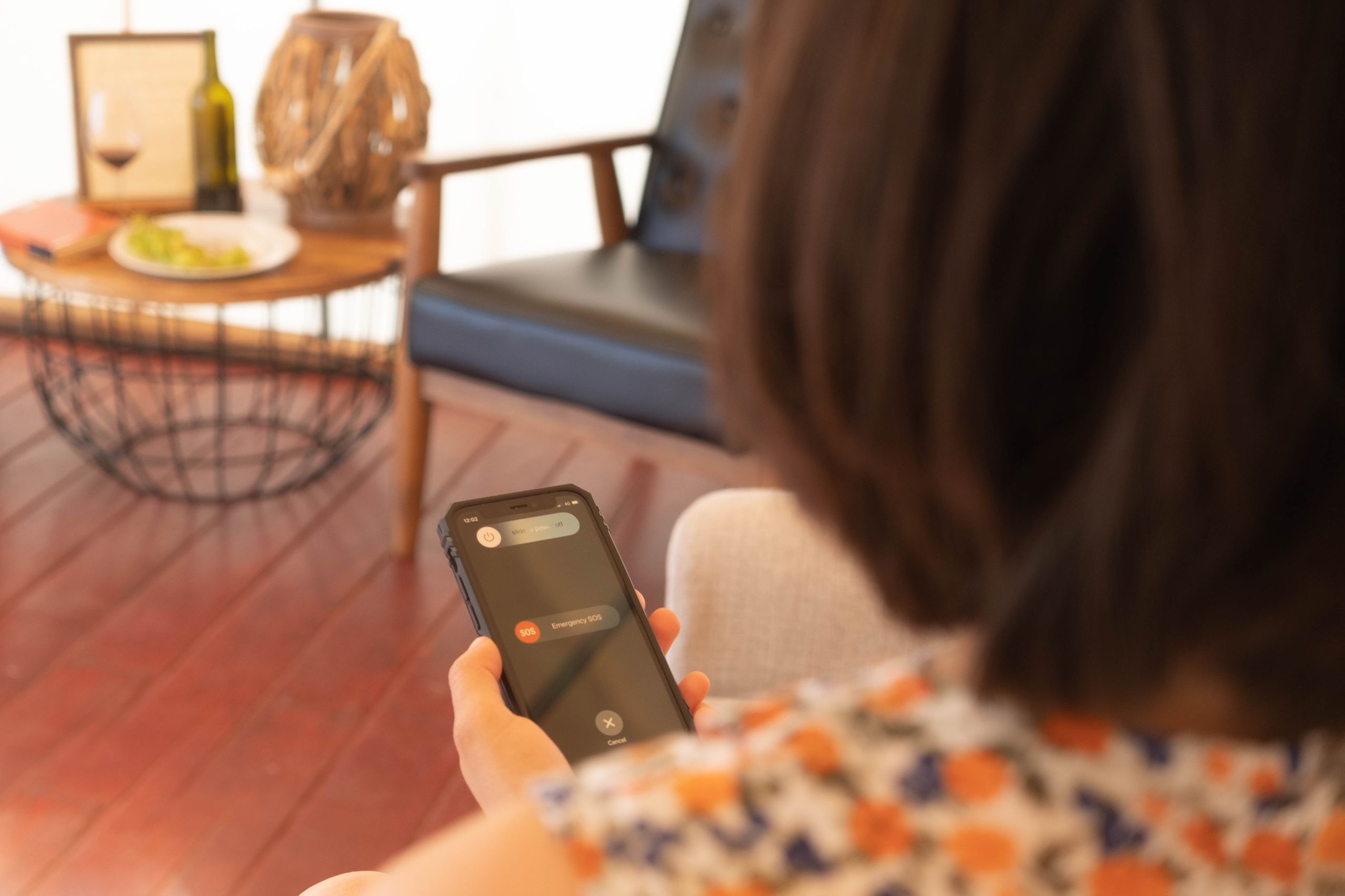 Airbnb Guest Communication: How to Keep Guests Happy Before, During, and After Their Stay - A person using a smartphone's SOS emergency feature indoors with a cozy background.