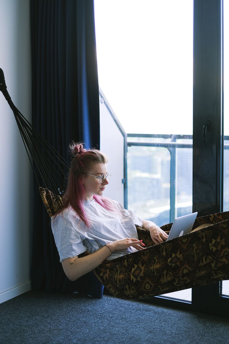 Airbnb Guest Screening Tips: How to Protect Your Home While Welcoming Great Guests - A woman relaxes in a hammock indoors while working on her laptop, embodying the digital nomad lifestyle.