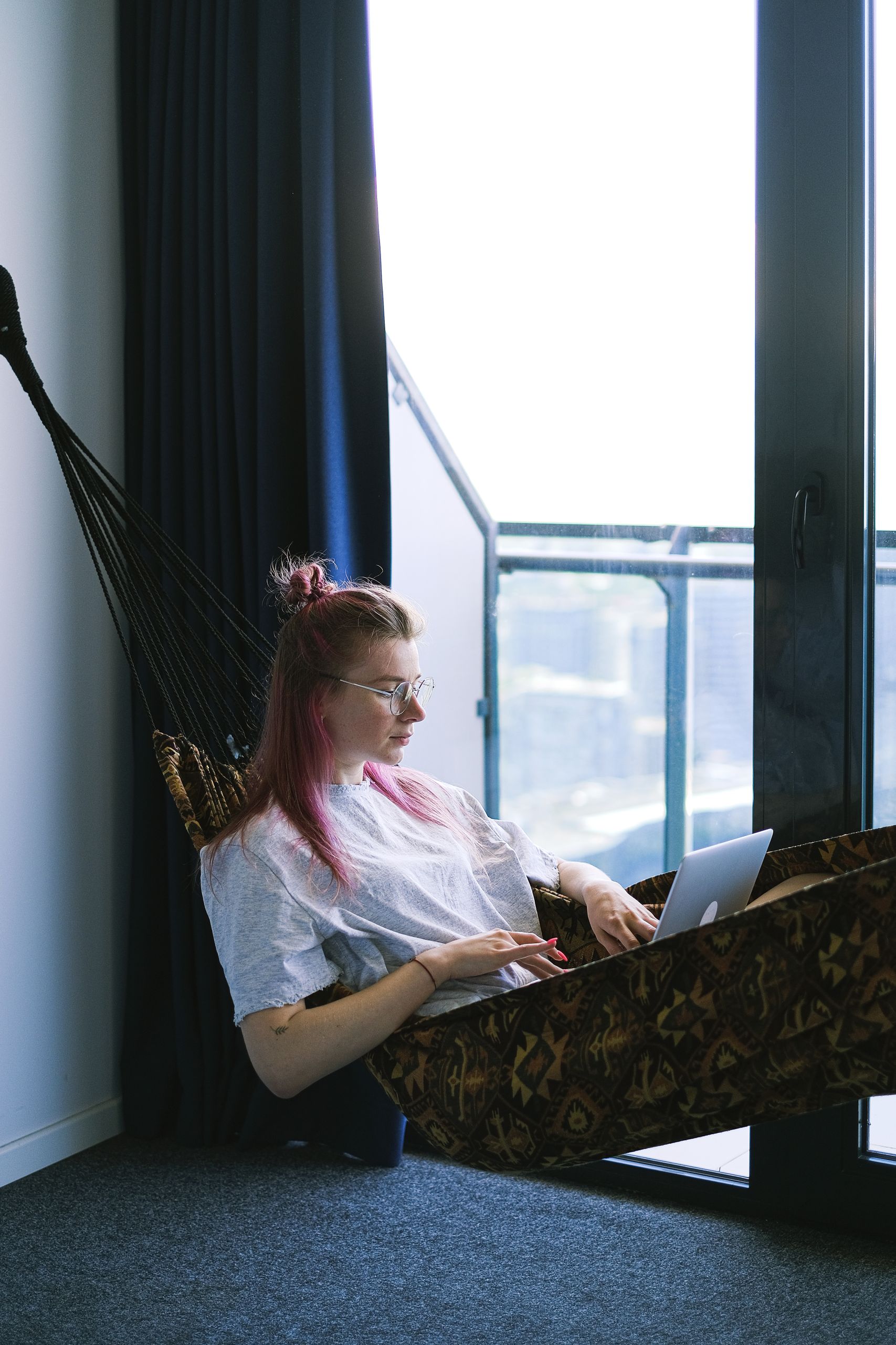 Airbnb Guest Screening Tips: How to Protect Your Home While Welcoming Great Guests - A woman relaxes in a hammock indoors while working on her laptop, embodying the digital nomad lifestyle.