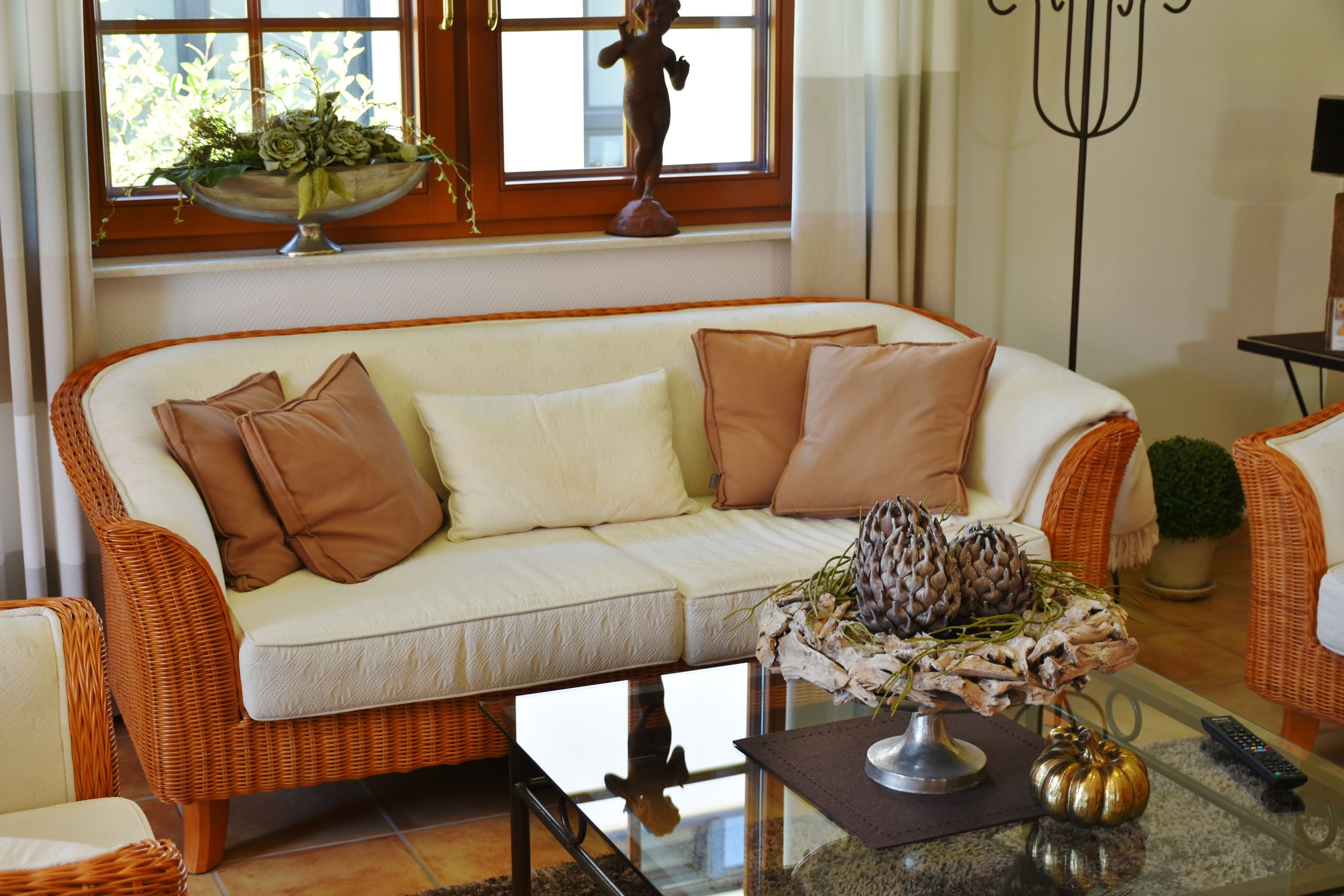 Airbnb Living Room Ideas: How to Create a Space Guests Love to Relax In - Elegant living room featuring a wicker sofa, cushions, and artistic decor pieces.