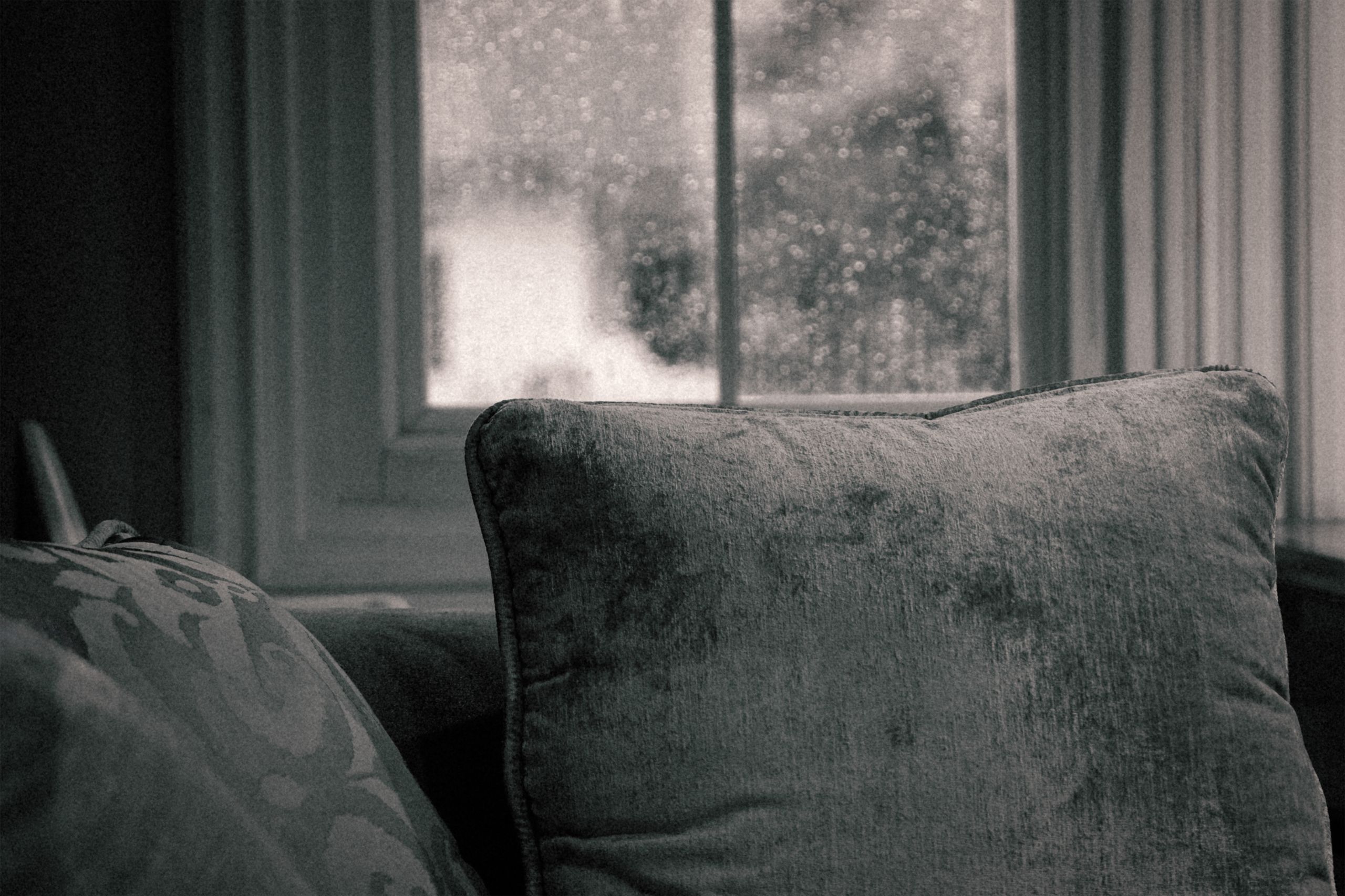 Airbnb Natural Disaster Preparedness: How to Protect Guests and Your Property - A cozy indoor setting with soft pillows by a rainy window, evoking comfort.