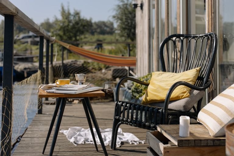 Airbnb Outdoor Spaces: How to Turn Patios, Porches, and Backyards into Five-Star Amenities - Relaxing outdoor porch scene with chair, table, and hammock for a perfect summer day.
