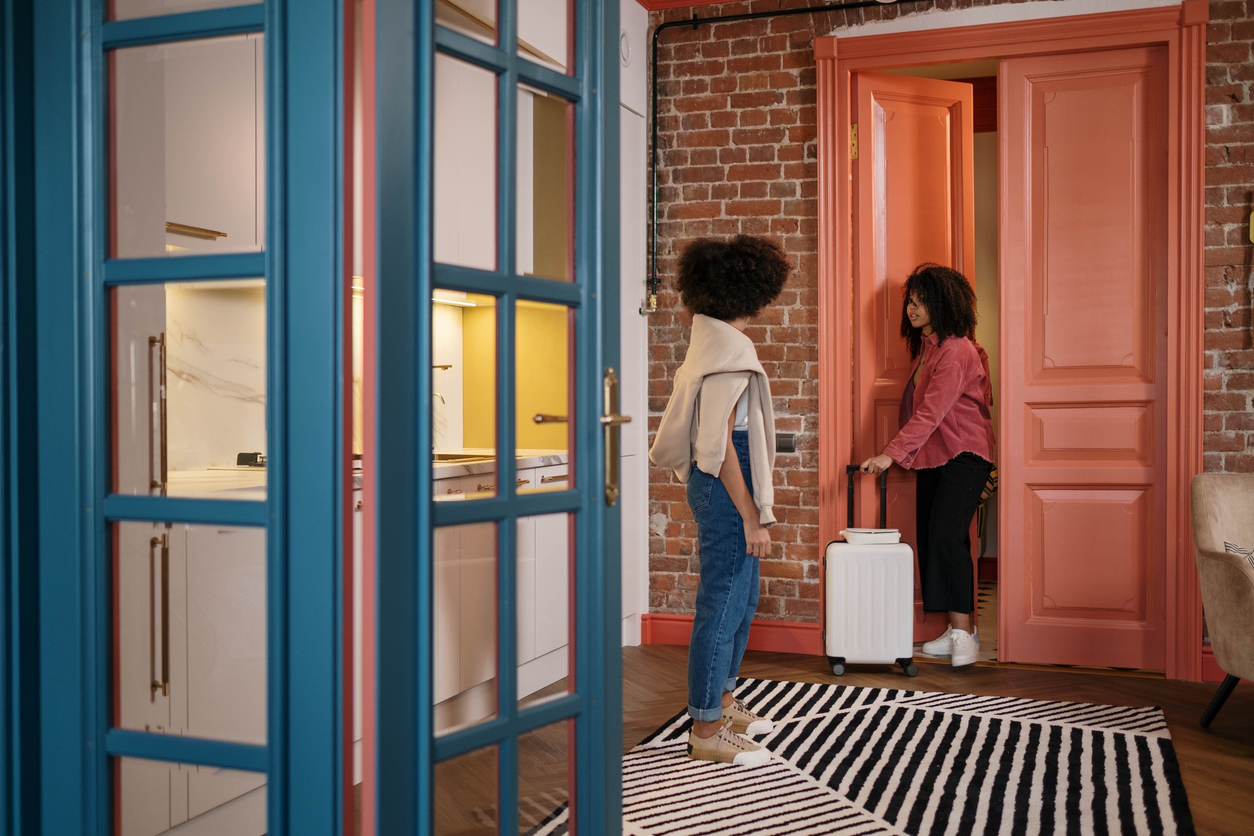 Airbnb Peak Season: How to Maximize Bookings During High-Demand Travel - Two women with luggage in a stylish apartment hallway, getting ready to travel.