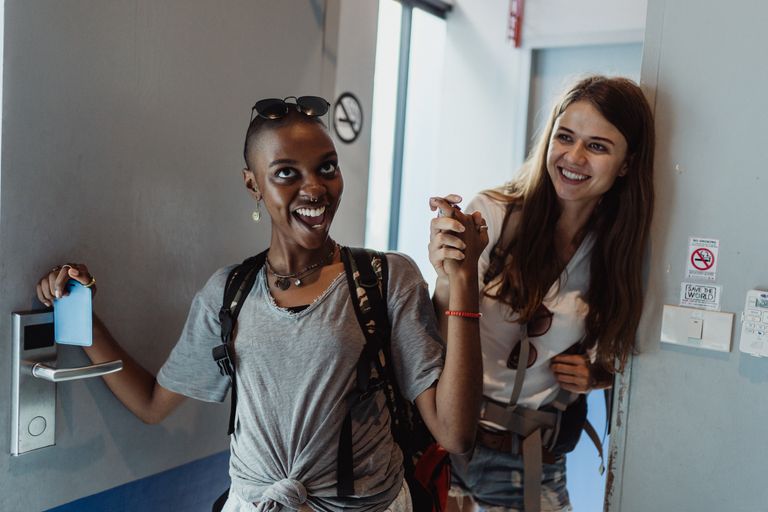 Airbnb Superhost Tips: Habits That Help You Earn and Keep Superhost Status - Two cheerful women entering a modern room, capturing moments of fun and friendship.