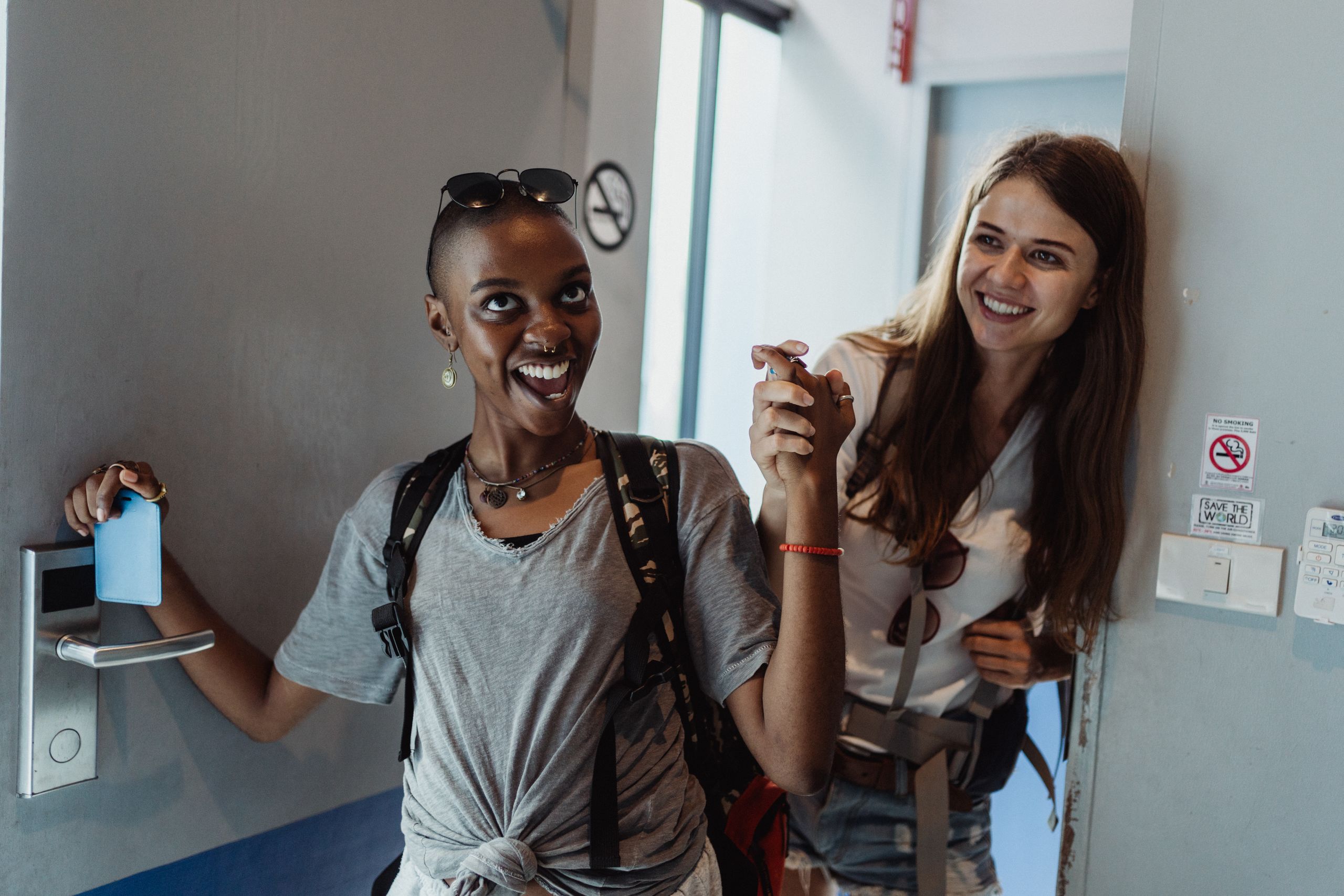 Airbnb Superhost Tips: Habits That Help You Earn and Keep Superhost Status - Two cheerful women entering a modern room, capturing moments of fun and friendship.