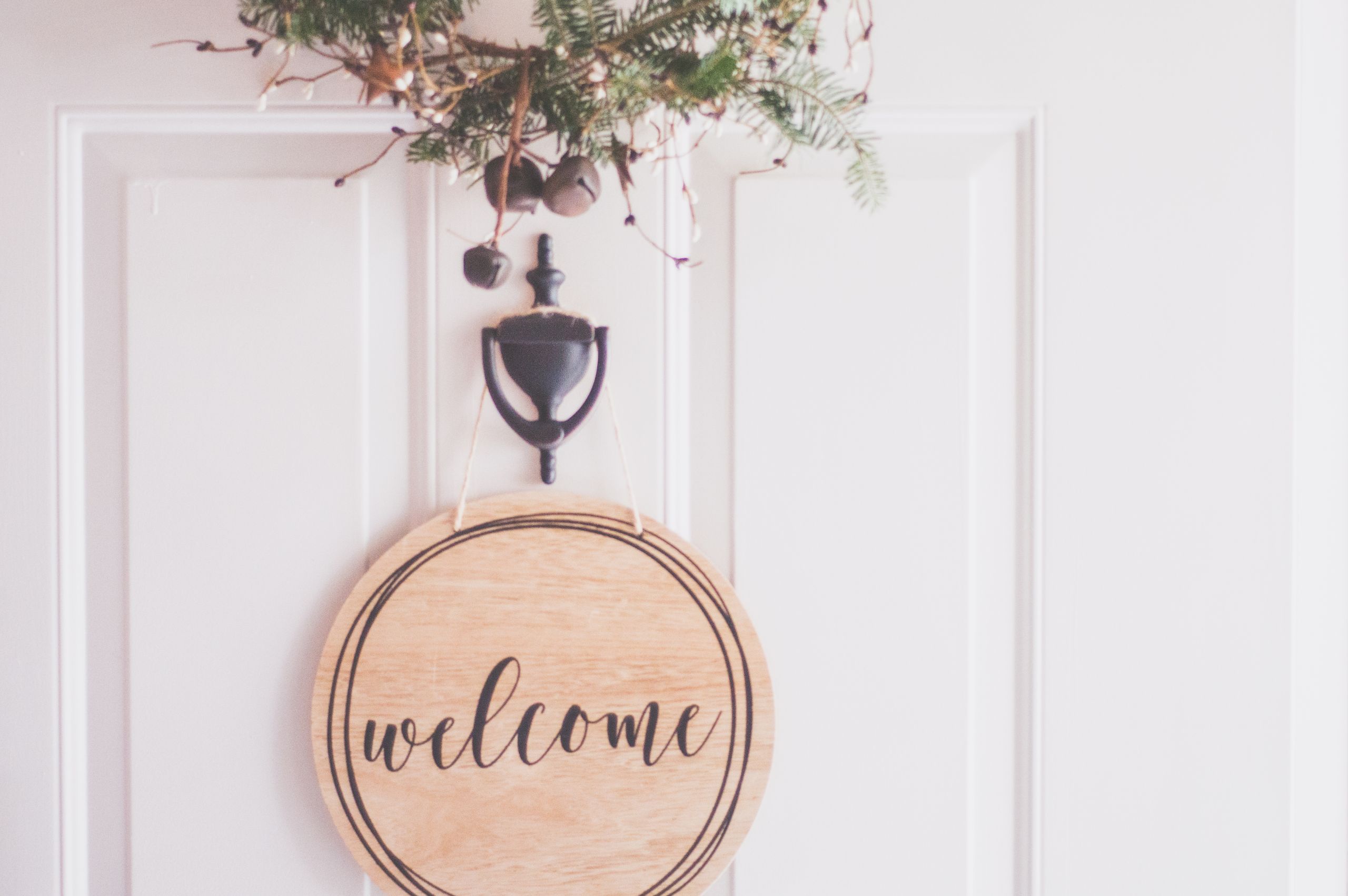 Airbnb Welcome Message Examples That Make Guests Feel at Home - A stylish welcome sign with festive greenery on a door, perfect for home decoration.