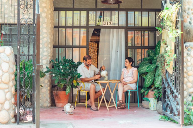 Eco-Friendly Airbnb: How Sustainable Hosting Attracts More Guests - Couple enjoying tea on a charming patio surrounded by lush plants and warm atmosphere.