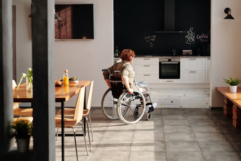 How to Host Guests with Mobility Challenges: Creating an Accessible Airbnb - A woman in a wheelchair moves through a bright kitchen and dining area, emphasizing home accessibility.