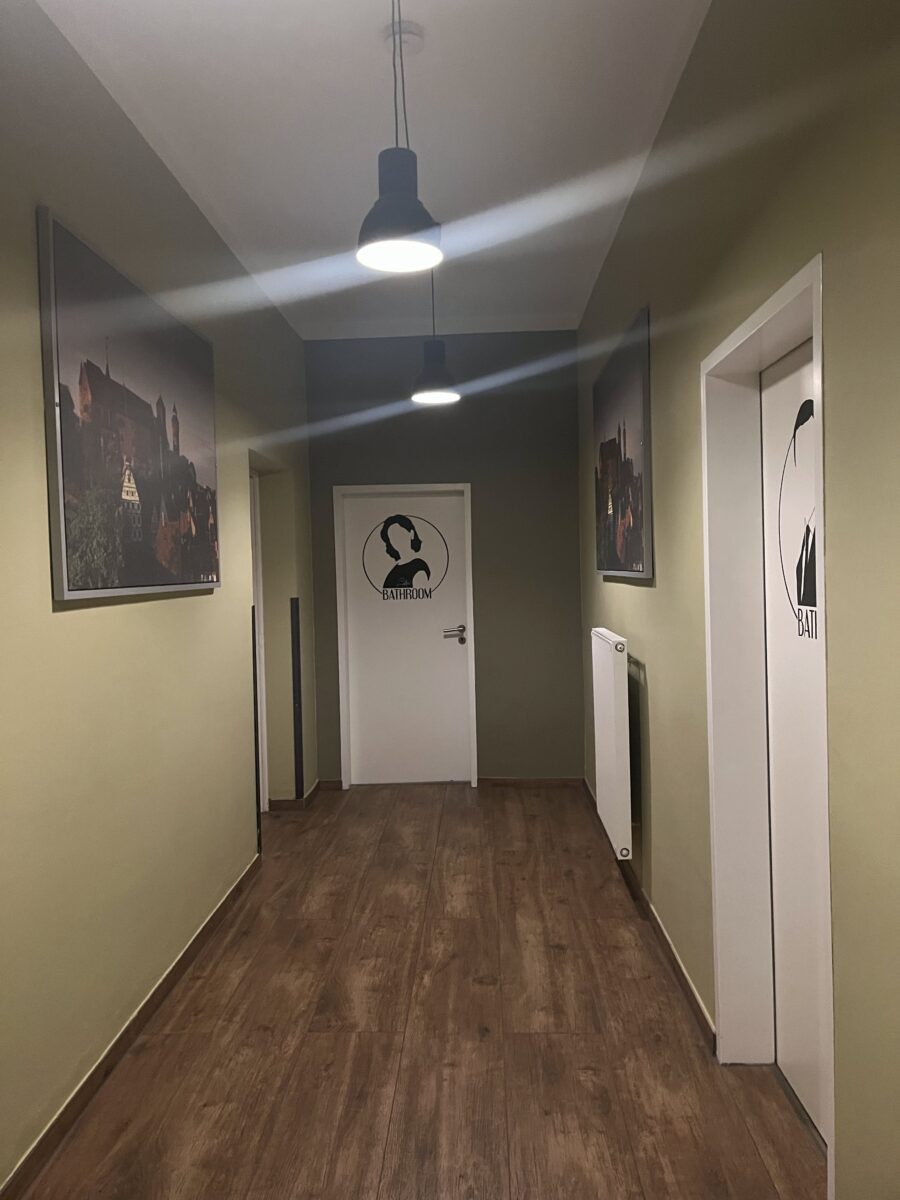 Clean hostel hallway with separate bathroom doors and photographs of Nuremberg Castle