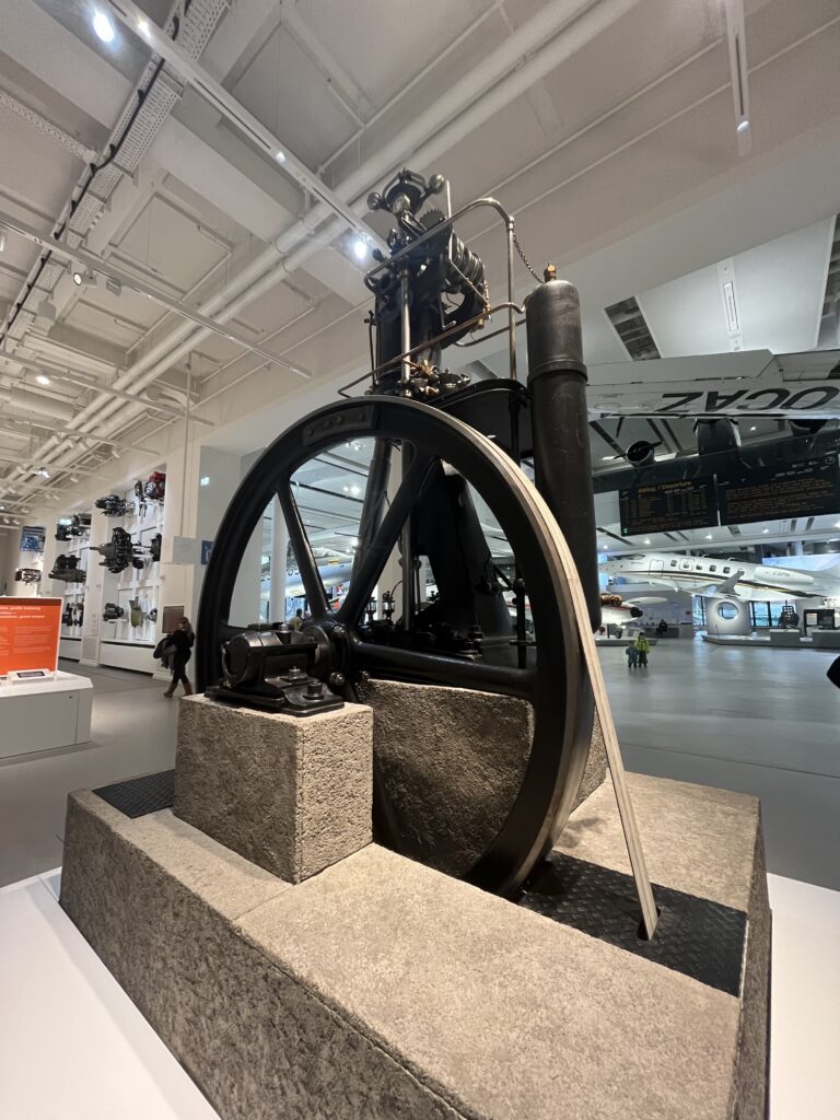 Large historic engine with a metal flywheel displayed inside the Deutsches Museum in Munich