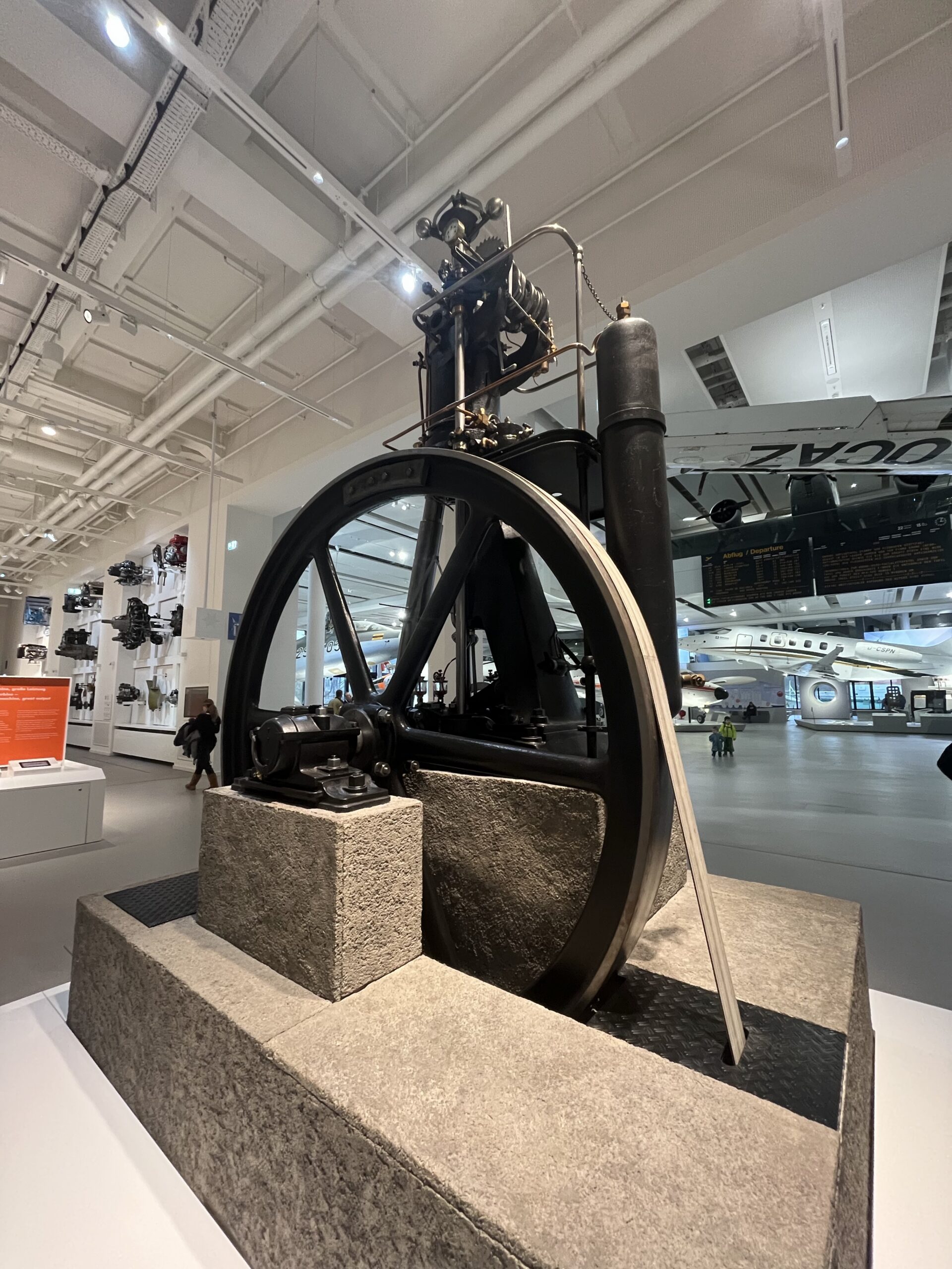 Large historic engine with a metal flywheel displayed inside the Deutsches Museum in Munich