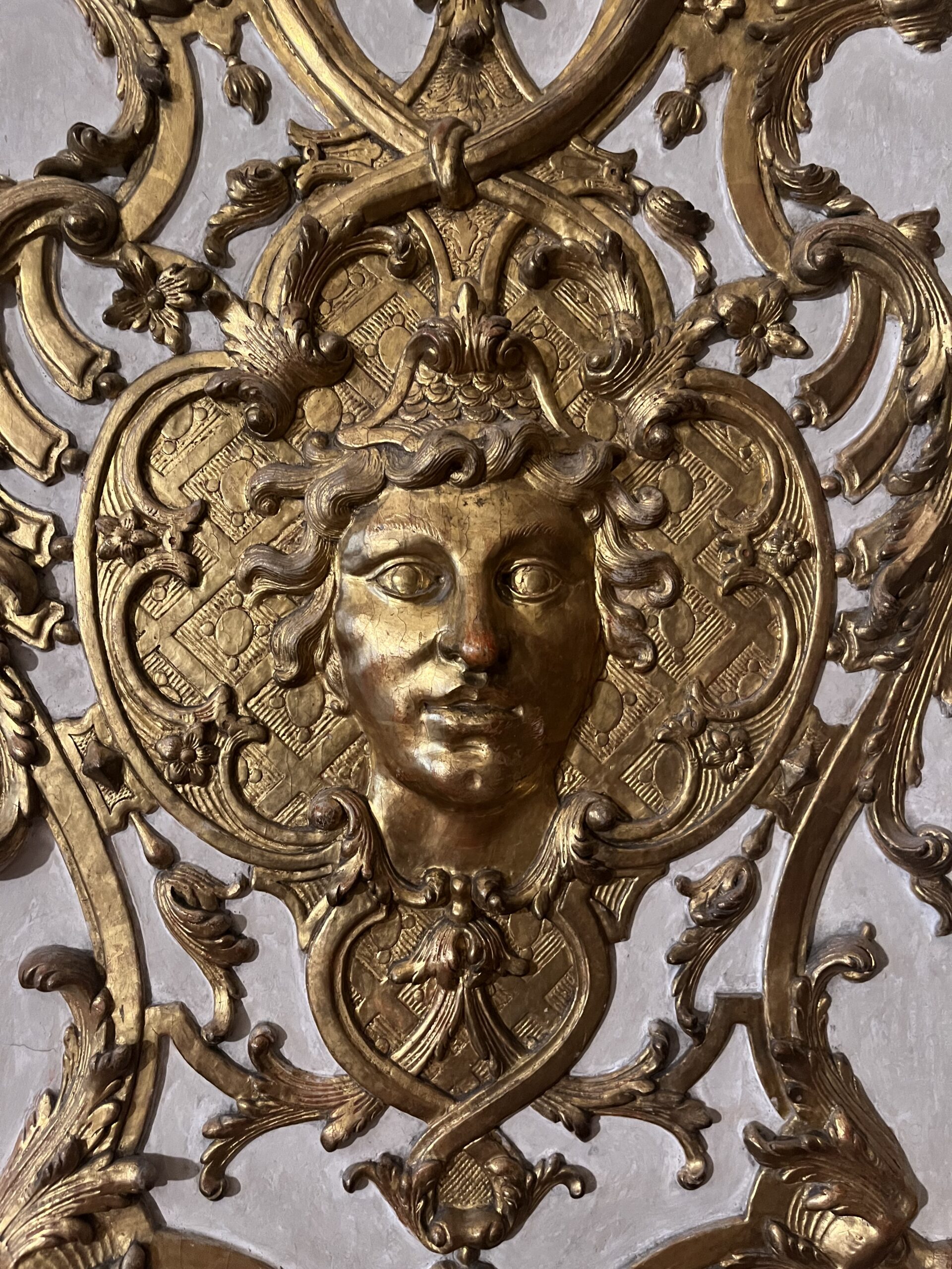 Gilded sculpted face surrounded by floral scrollwork at the Munich Residenz