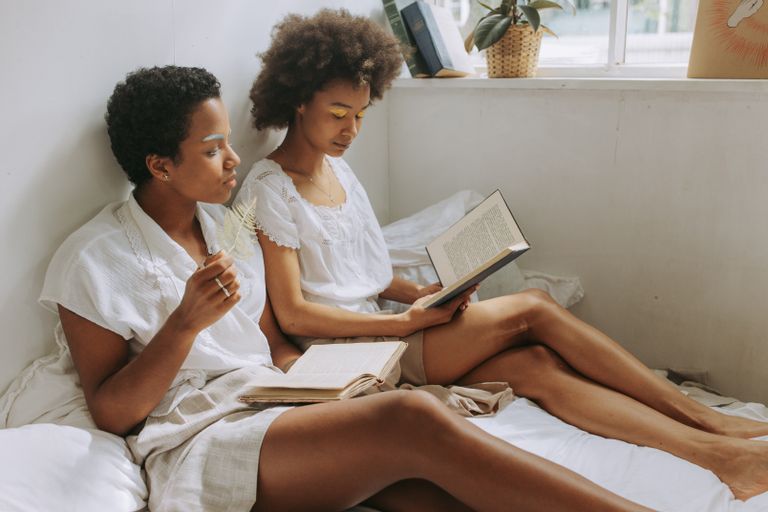 5 Self-Discovery Books by Black Women - Two women with afro hair reading books in a cozy, sunlit room with calm interior decor.