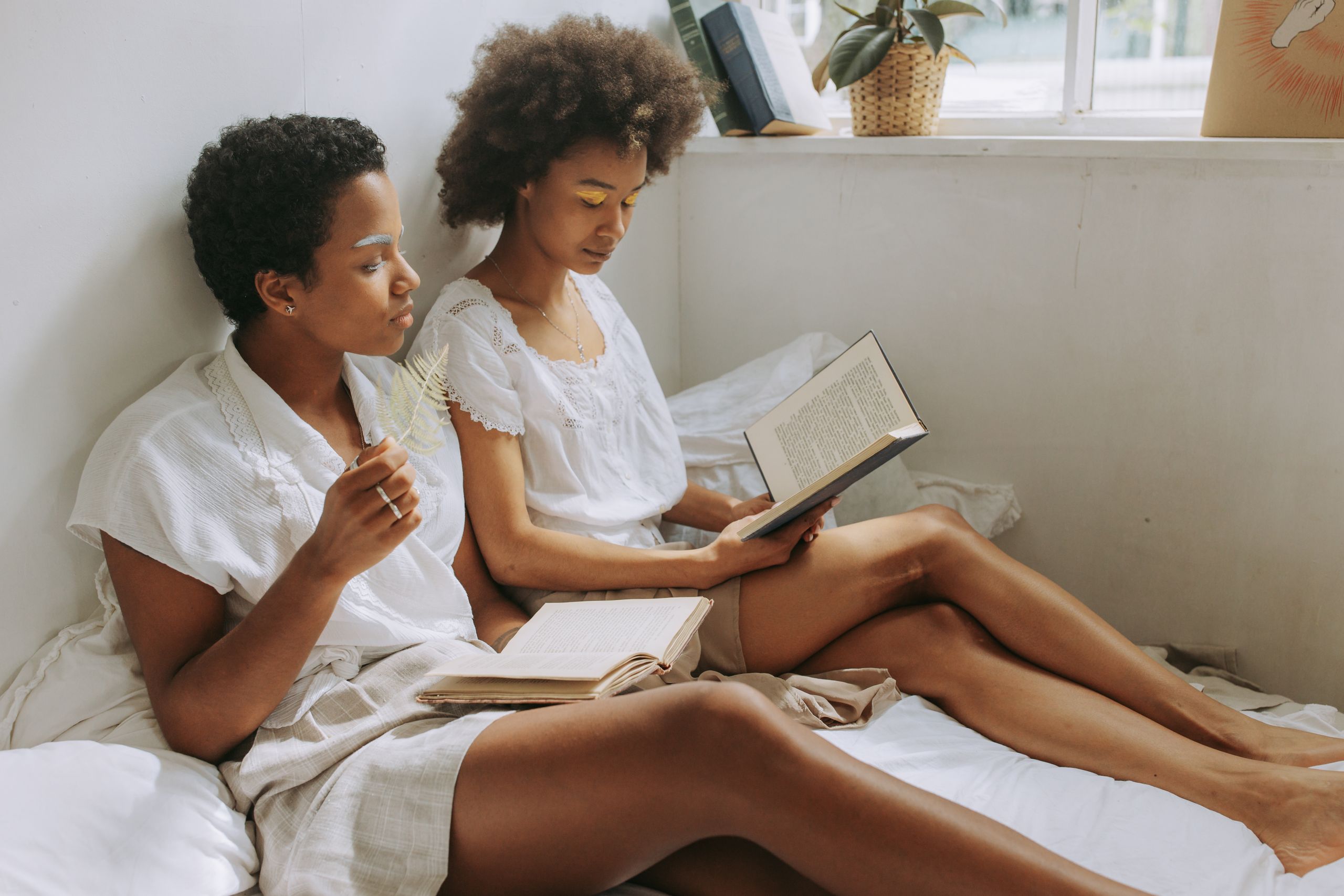 5 Self-Discovery Books by Black Women - Two women with afro hair reading books in a cozy, sunlit room with calm interior decor.