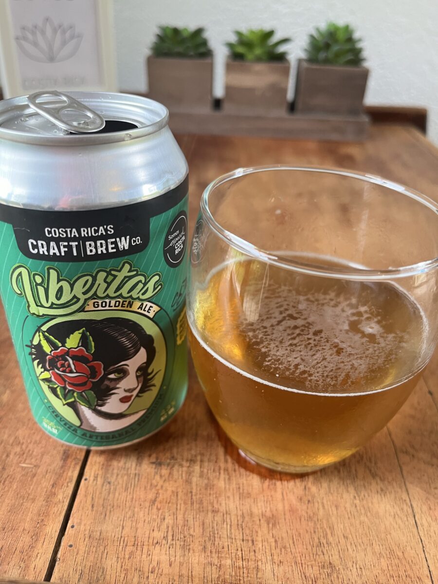 Can of Libertas Golden Ale beside a freshly poured glass of Costa Rican craft beer.