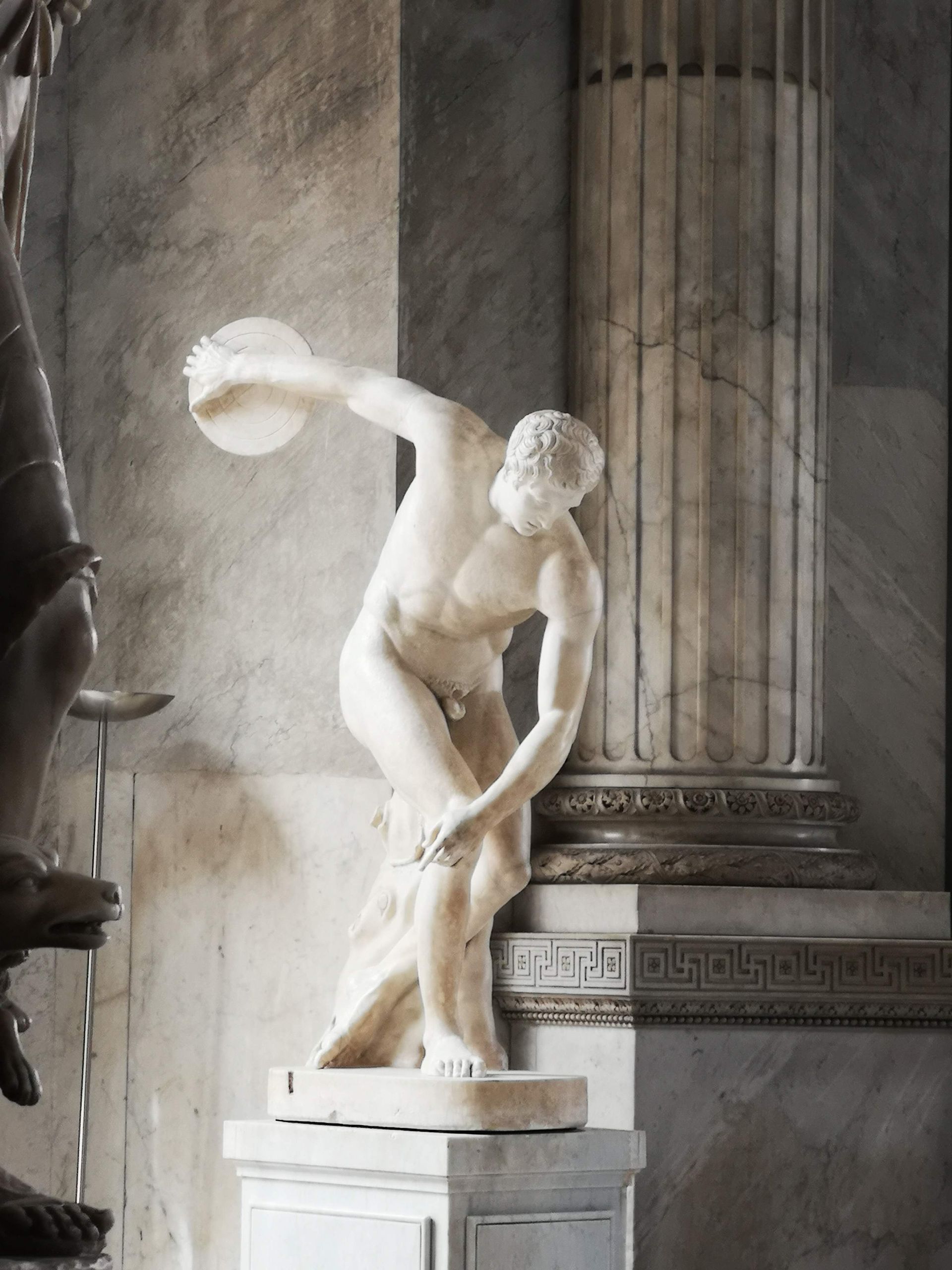 A marble sculpture of the Discobolus displayed indoors at a Vatican City museum.