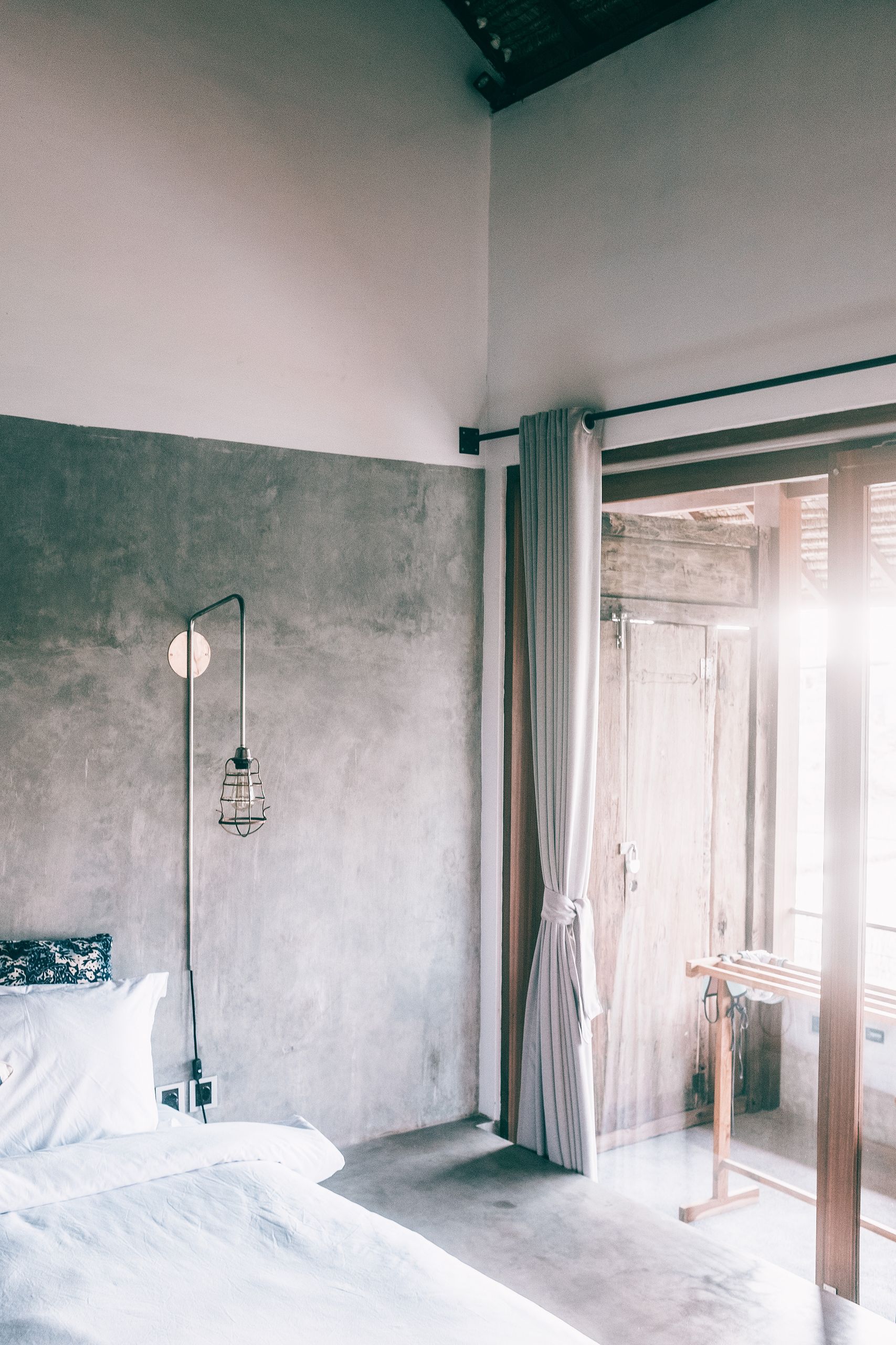 Beauty of a Room With Good Light - Bed with soft blanket and pillow near lantern on concrete wall illuminated by shiny light in house