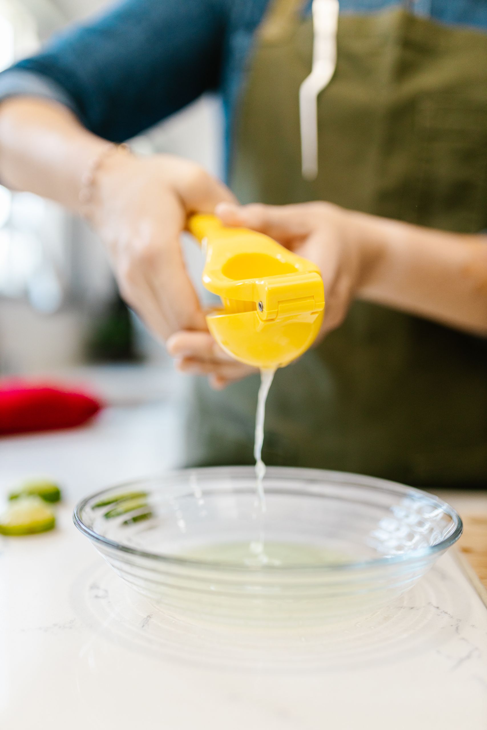 Benefits of Drinking Hot Lemon Water Every Day - Close-up of hands squeezing fresh lime juice into a clear bowl for cooking purposes.