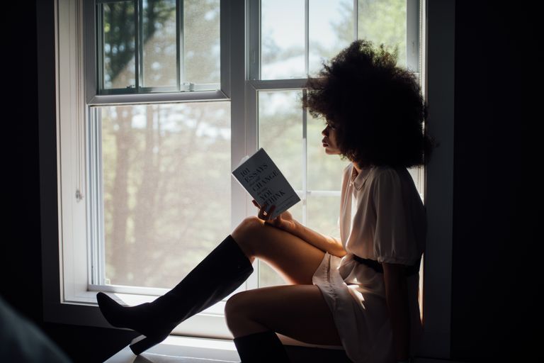 Best Books to Read - A woman enjoys a peaceful reading session by a window, bathed in natural light.