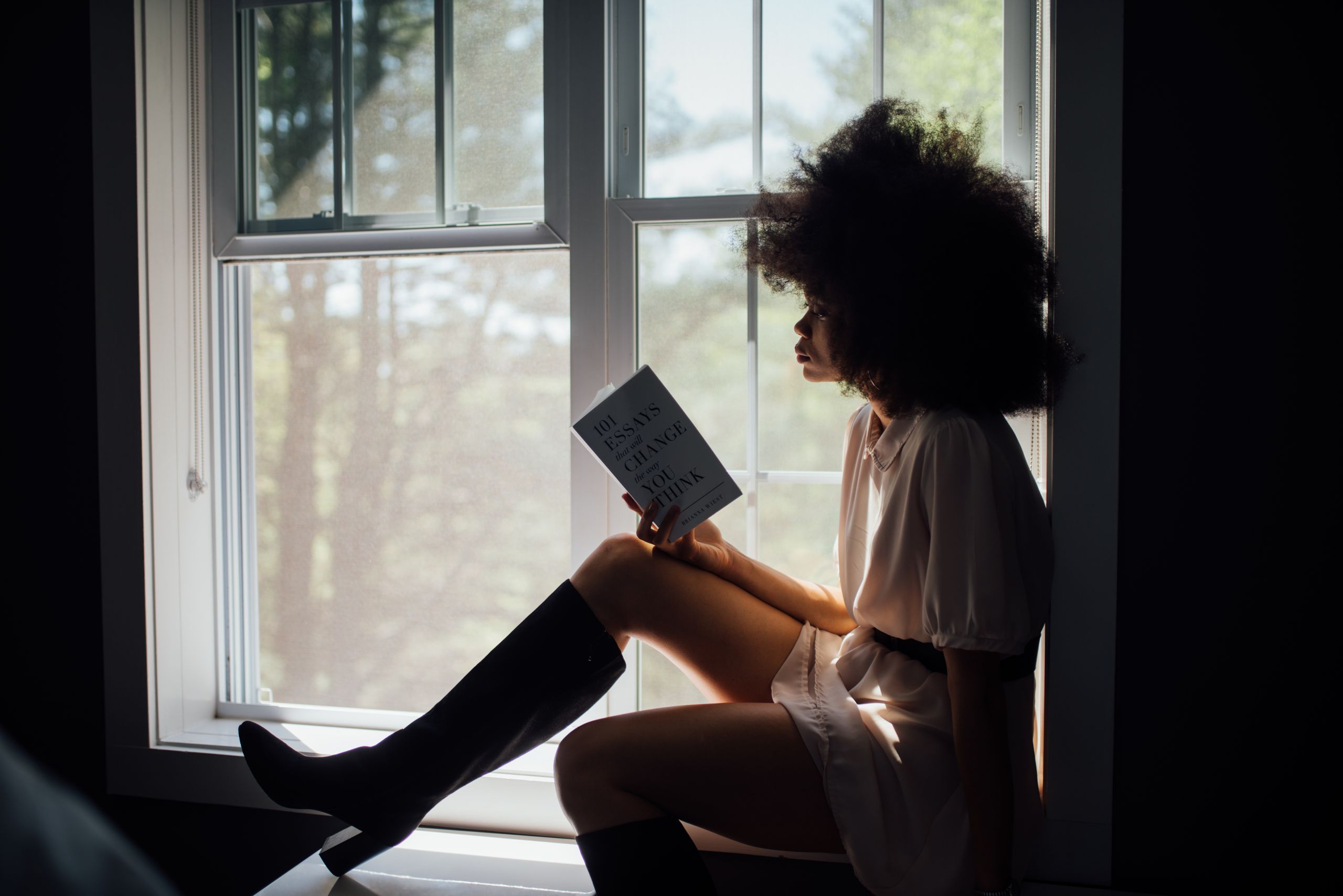 Best Books to Read - A woman enjoys a peaceful reading session by a window, bathed in natural light.