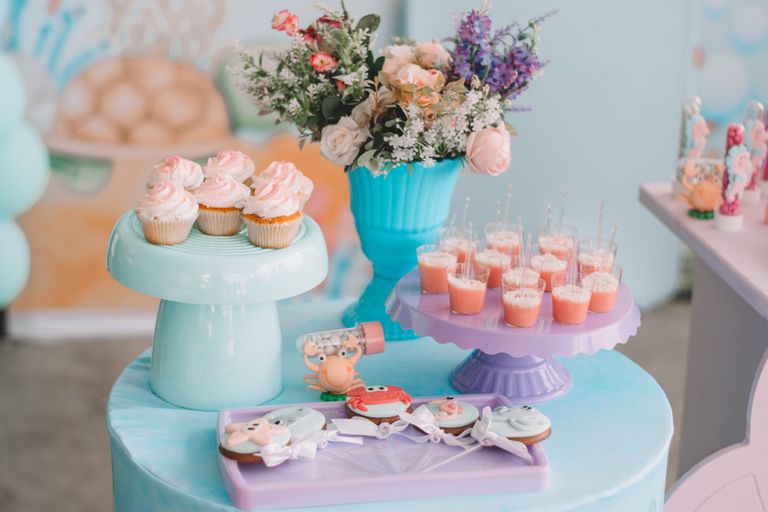 Birthday Table - A vibrant dessert table with cupcakes, cookies, flower arrangements, and pastel decorations.