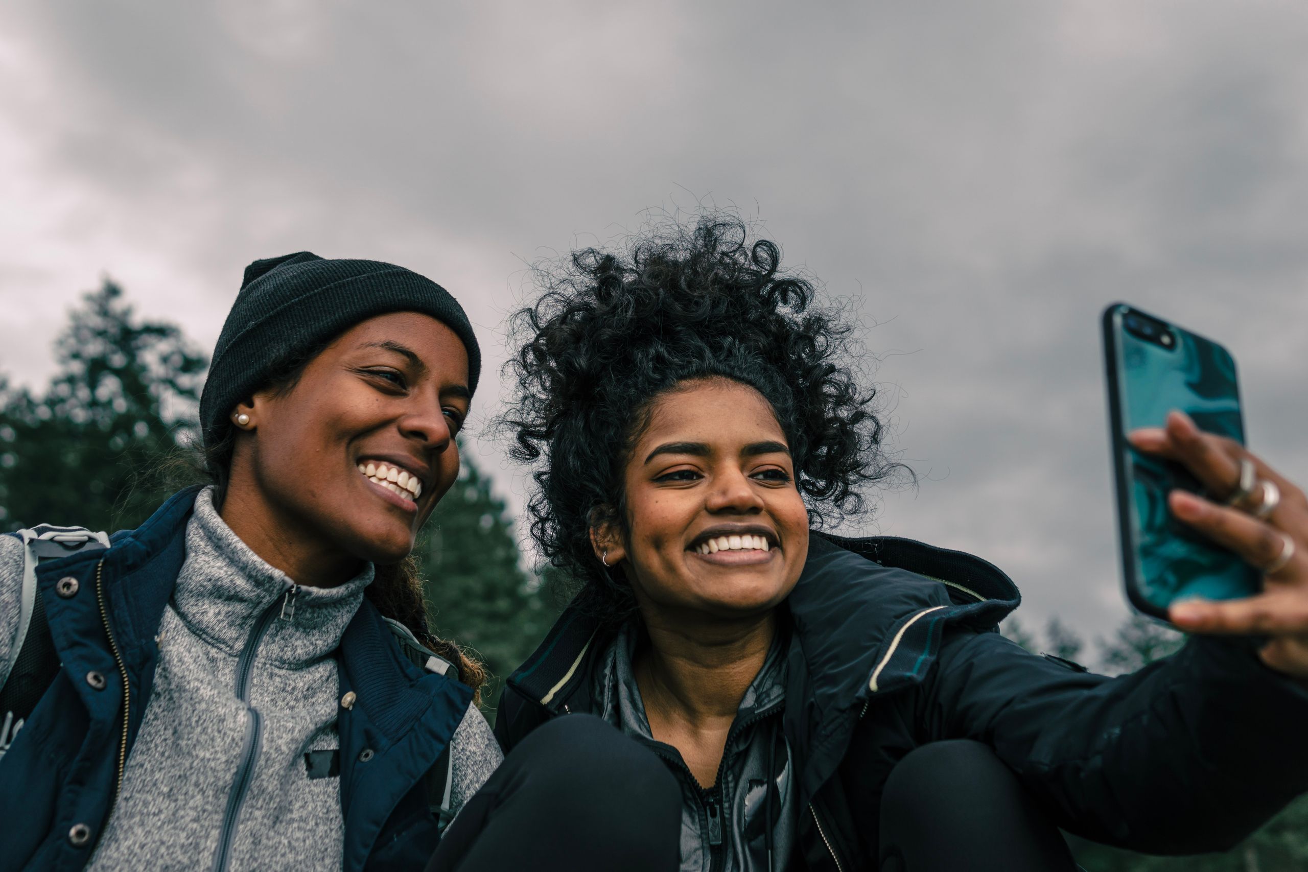 Black Women Travel With Memory in Our Suitcases - Two women joyfully capturing a selfie in an outdoor setting, showcasing happiness and friendship.
